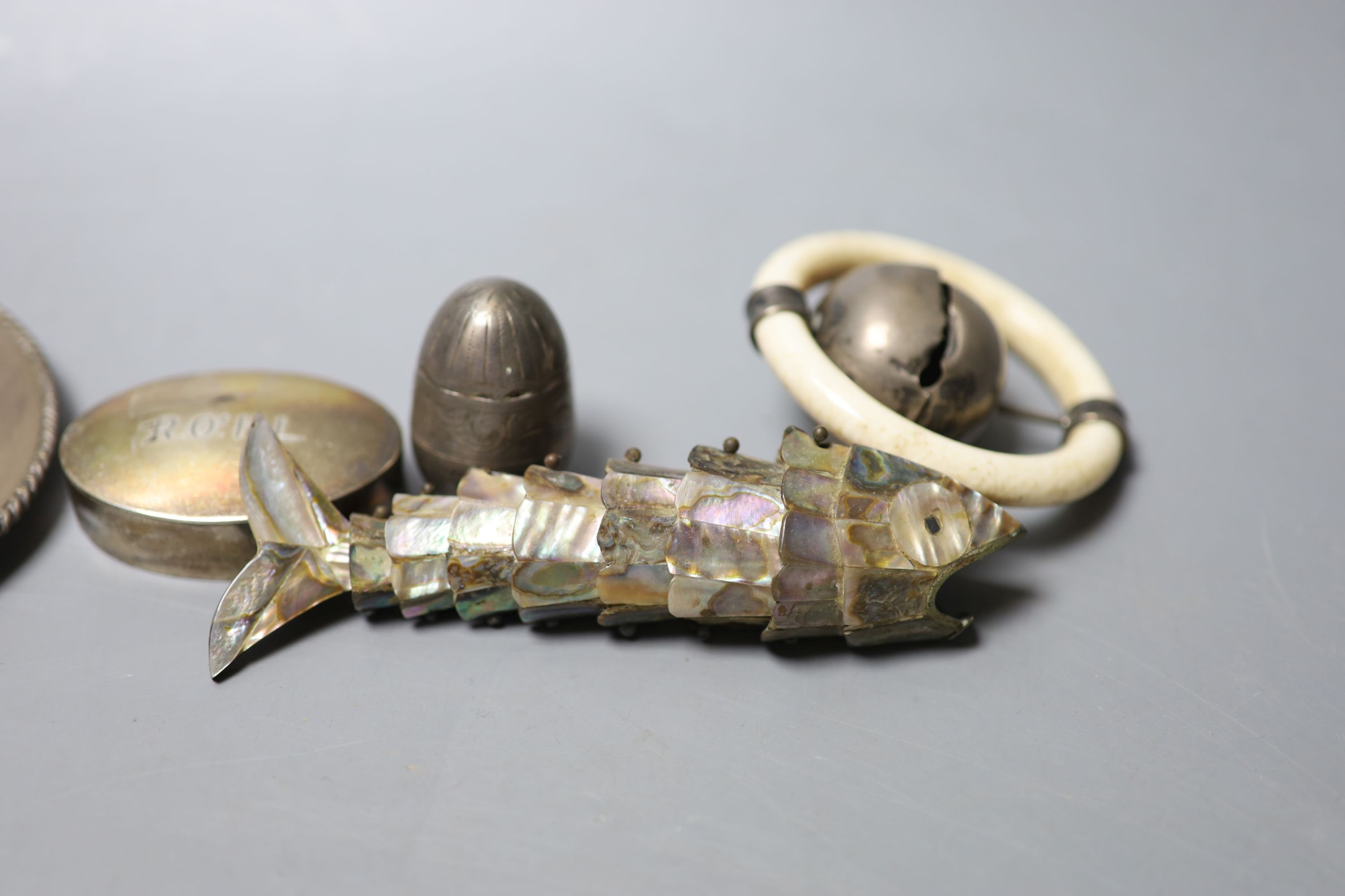 A silver and ivory baby's rattle with teething ring and a Mexican sterling 'hat' snuffer and three other items, including a mother of pearl mounted articulated fish and a silver pill box.